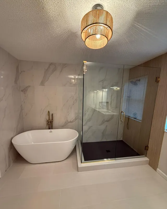 Frameless shower glass next to a freestanding tub under a pendant light
