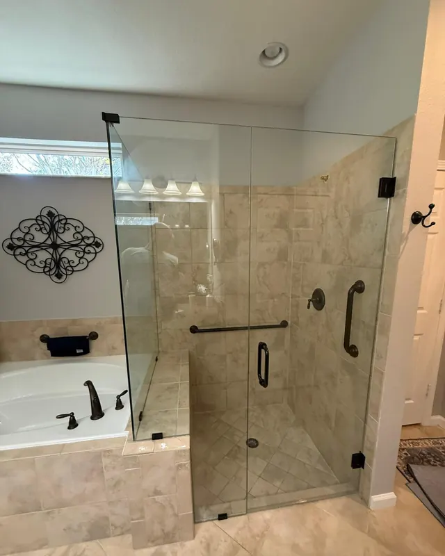 Corner frameless shower enclosure with black hardware next to a soaking tub