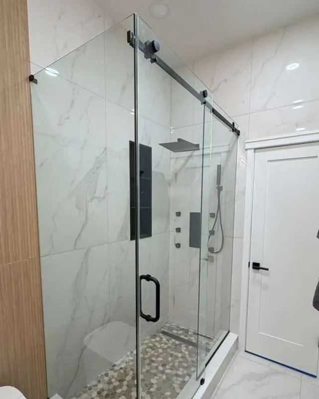 Corner frameless shower enclosure with black hardware and large format marble tile